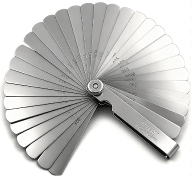 Feeler gauge blades checking valve clearance on an engine